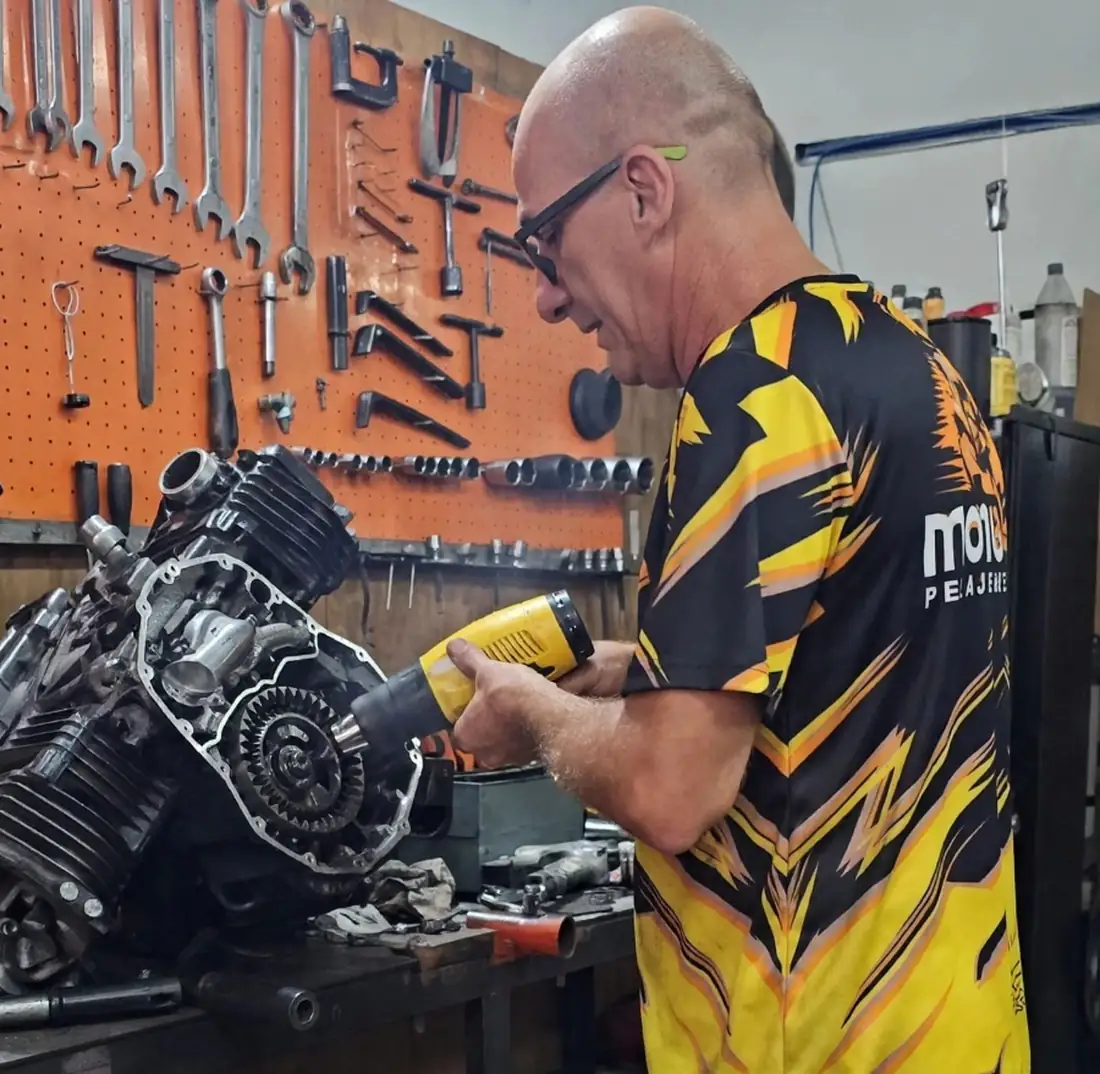 Dono da Motobonas trabalhando no motor de uma moto